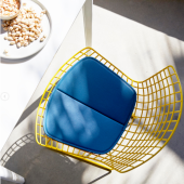 Sedia Bertoia Side Chair del brand Knoll, struttura gialla in metallo con cuscino azzurro, adatta per esterni e interni.