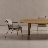 Elegante Sedia Salinas by Kettal posizionata accanto a un tavolo in legno ovale in uno spazio minimalista con pavimento in cemento