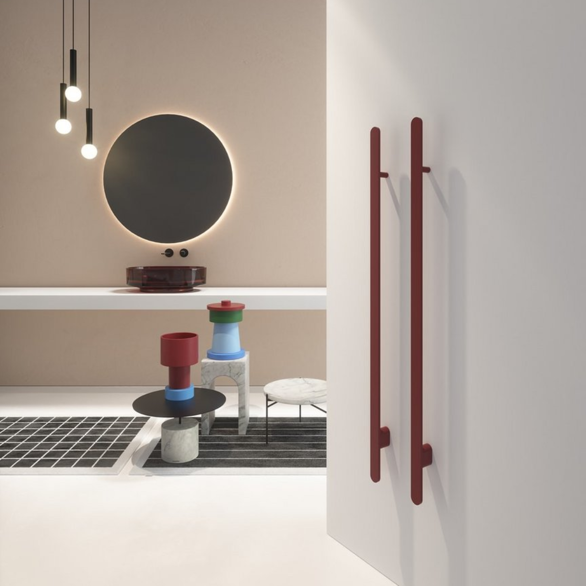 scaldasalviette-rigo-antoniolupi-latohome Scaldasalviette Rigo in ottone di Antonio Lupi posizionato verticalmente su una parete bianca con design minimale, accanto a un tavolino con oggetti di design e una lampada pendente in una stanza moderna e ben illuminata.