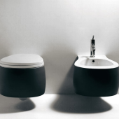 Eleganti sanitari Pear da Agape in bicolore con WC e bidet sospesi, rubinetto cromato, contro un muro chiaro per interni di lusso.