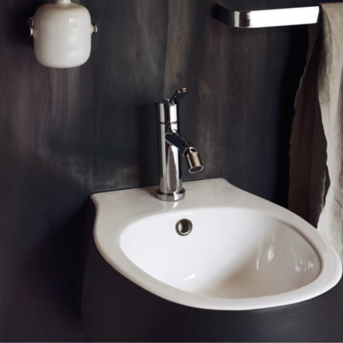 "Dettaglio del lavabo Pear 2 di Agape con rubinetto cromato su sfondo di parete testurizzata grigia - focus sul design