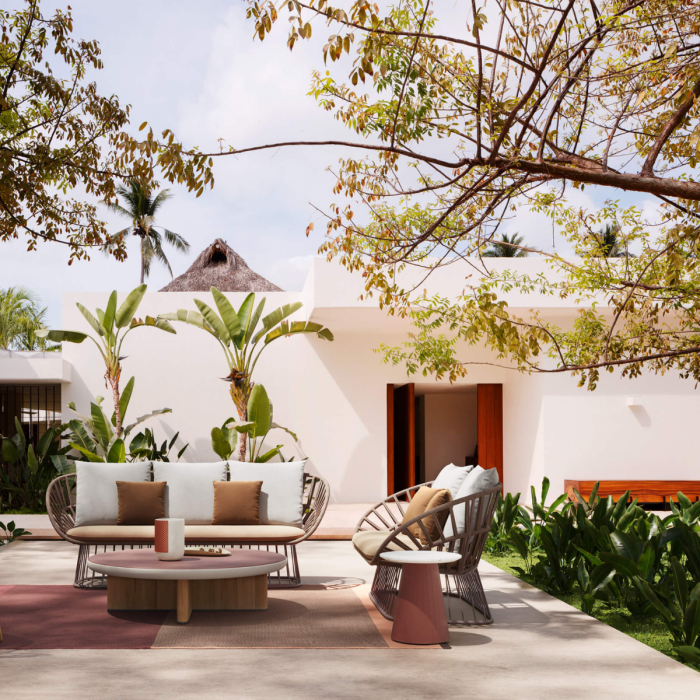 Divano Cala di KETTAL posizionato in un'elegante veranda esterna con vegetazione tropicale e architettura moderna