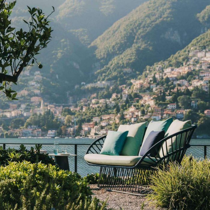 Divano Cala di KETTAL su terrazza vista lago con dettaglio del tessuto dei cuscini verde acqua e decorazioni naturali, enfatizzando il design e il comfort all'aperto.
