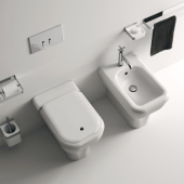 Sanitari a terra Memory di Agape in un bagno elegante con finiture bicolore e rubinetteria in metallo, su pavimento e parete in grigio.