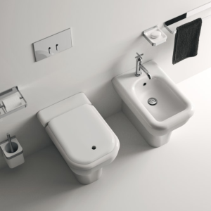 Sanitari a terra Memory di Agape in un bagno elegante con finiture bicolore e rubinetteria in metallo, su pavimento e parete in grigio.