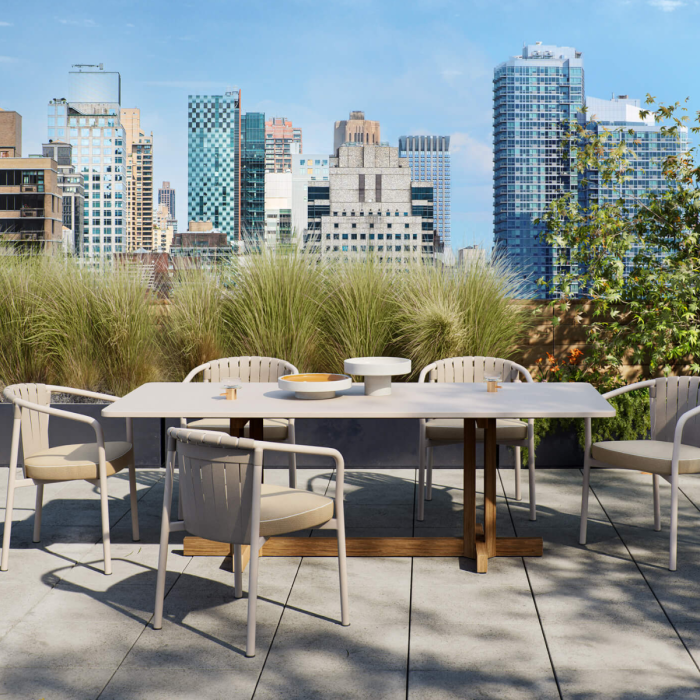 Moderno tavolo da pranzo Altar Boma di Kettal su terrazza all'aperto con sedie abbinabili, ambientazione urbana con grattacieli sullo sfondo, ideale per arredamento esterno di lusso e design moderno